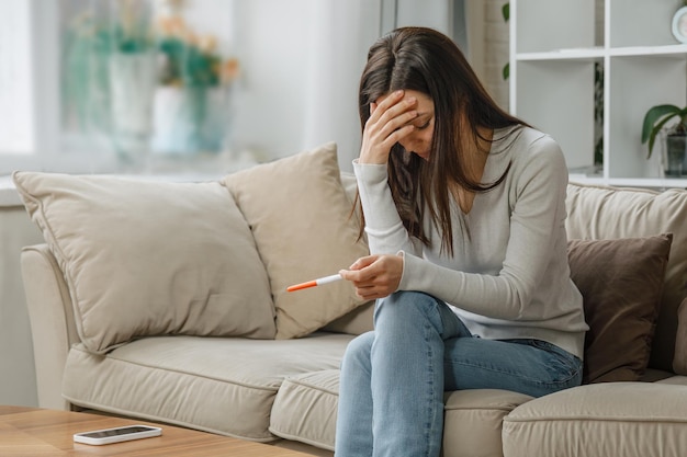 Mujer triste mirando una prueba de embarazo negativa
