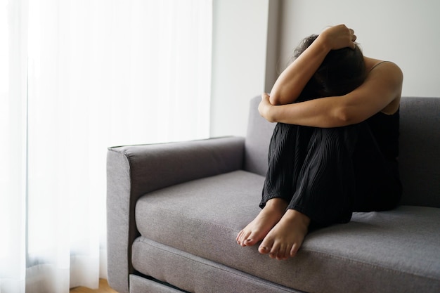 Una mujer triste pensando en problemas sentada en un sofá, una chica molesta que se siente sola y triste por una mala relación o una mujer deprimida que trastorna la salud mental