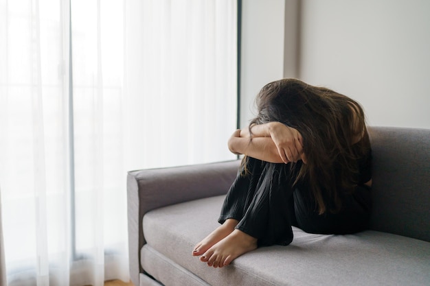 Mujer triste pensando en problemas sentada en un sofá chica molesta sintiéndose sola y triste por una mala relación o mujer deprimida trastorno de la salud mental