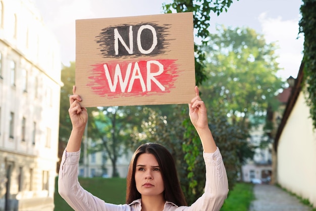 Mujer triste sosteniendo un cartel con las palabras No War en las calles de la ciudad