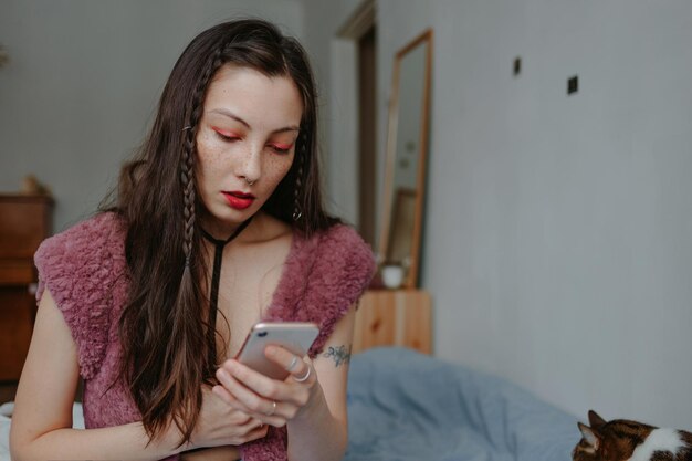 Foto mujer triste con teléfono inteligente en casa