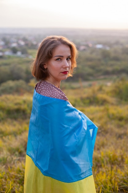 Mujer triste con vestido largo sosteniendo una bandera amarilla y azul de Ucrania