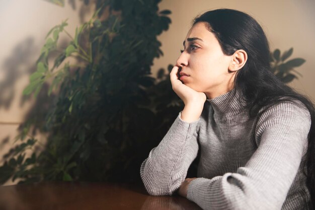 mujer tristemente mientras está sentada a la mesa en casa