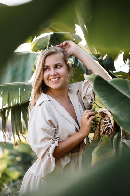 Mujer tropical exótica cerca de hojas verdes de arbusto de plátano. Chica de isla tropical de vacaciones