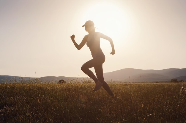 Mujer trotando corriendo en el campo de verano al atardecer