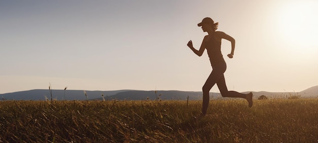 Mujer trotando corriendo en el campo de verano al atardecer