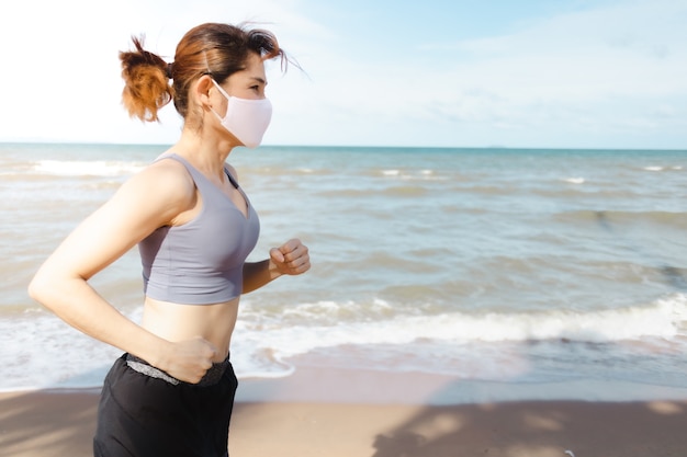 Mujer trotando por la playa en la mañana del cálido verano