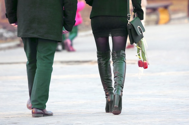 Mujer con tulipanes de flores en la mano, caminando junto al hombre. cita de una pareja amorosa en un paseo