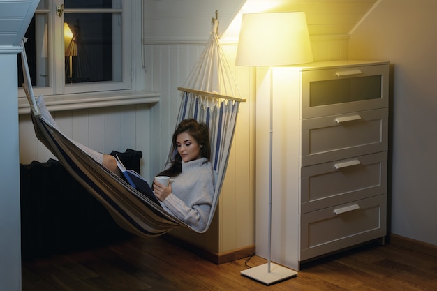 Mujer tumbada en la hamaca y leyendo el libro