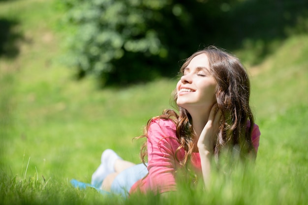 Mujer tumbada en la hierba y sonriendo