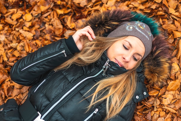 una mujer tumbada en las hojas de otoño