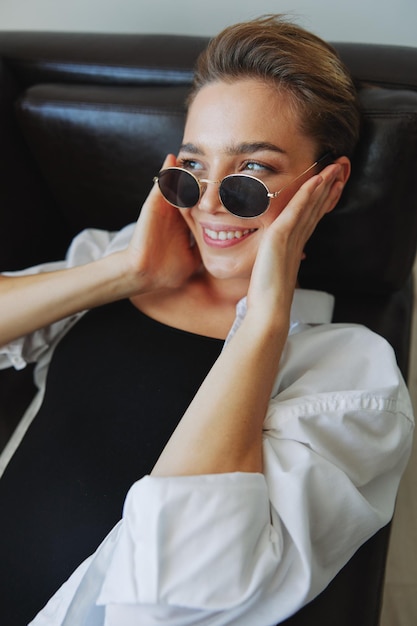 Una mujer tumbada en el sofá con las gafas puestas y retorciéndose Foto de alta calidad