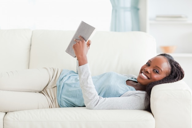 Mujer tumbada en el sofá leyendo una novela