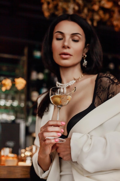 Mujer con túnica blanca sosteniendo una copa de vino