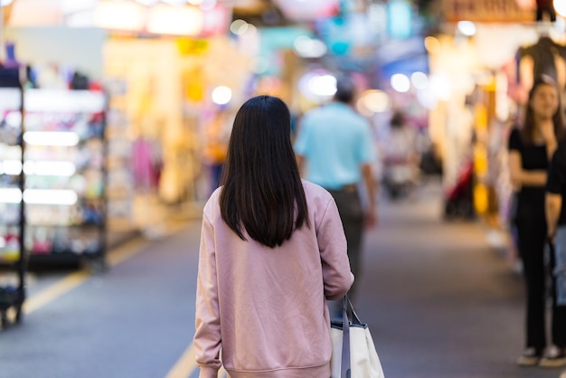 Mujer turista va al mercado callejero por la noche en Taiwán