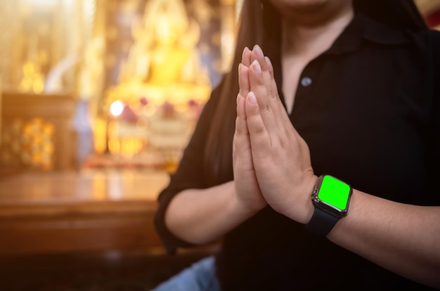 Foto mujer turista asiática de primer plano paga respeto con la mano usando un reloj inteligente de pantalla verde