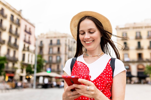 Foto mujer turista blanca adulta joven que usa el teléfono móvil mientras camina en la calle