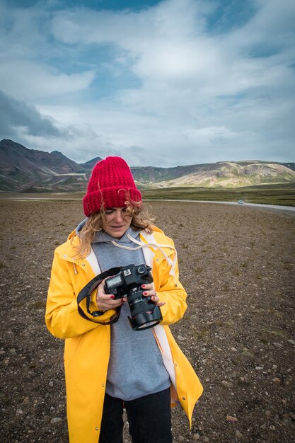 Mujer turista con cámara de pie cerca de hermoso paisaje islandia