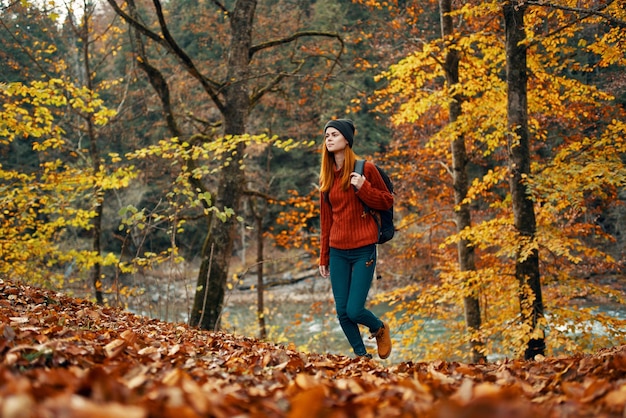 Foto mujer turista camina por el parque en otoño con una mochila en la espalda y árboles altos paisaje río lago foto de alta calidad