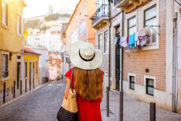 Mujer turista caminando de regreso por la calle angosta en la región de Alfama durante la luz de la mañana en Lisboa, Portugal.