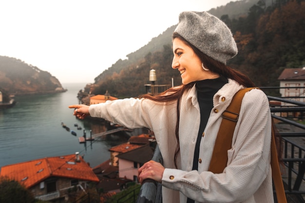 Mujer turista caucásica joven que mira la bahía desde un alto punto de vista en Pasaia; País Vasco.