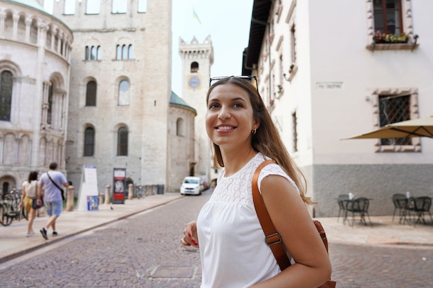 Mujer turista feliz visitando la antigua ciudad medieval de Trento, Italia