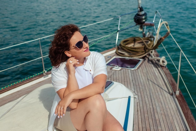 Mujer turista con gafas de sol en un día de verano en un yate en el mar