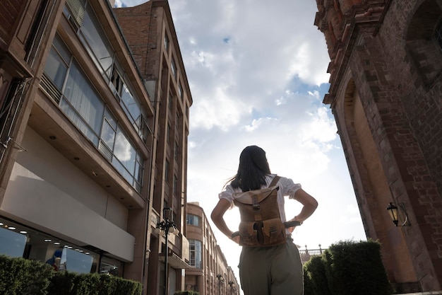 Mujer turista irreconocible de espaldas caminando en un paisaje urbano al atardecer