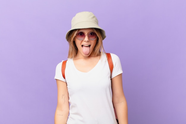 Mujer turista joven viajero con actitud alegre y rebelde, bromeando y sacando la lengua