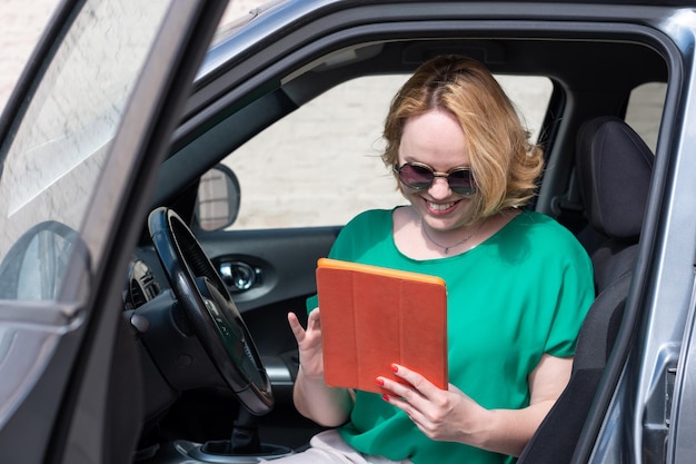 Mujer turista mira el camino en el navegador consulta con la guía en la tableta mientras está sentada en el auto