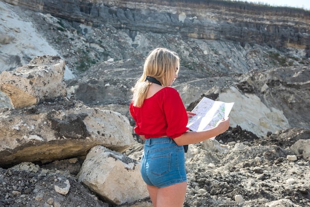 Mujer turista mira el mapa entre las piedras con cámara