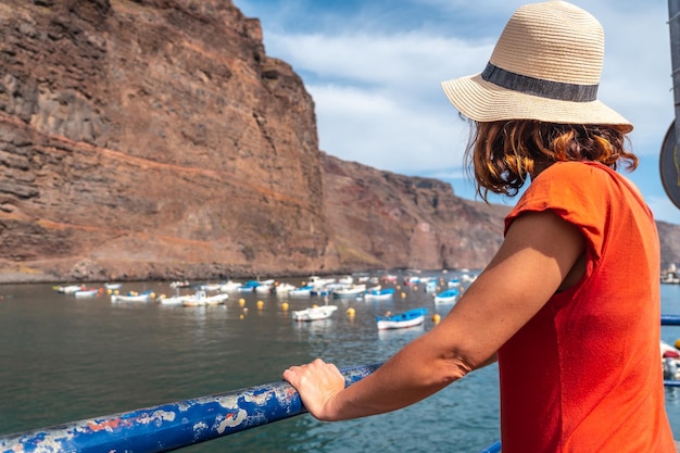 Una mujer turista mirando la playa desde el puerto pesquero del pueblo de Valle Gran Rey en La Gomera, Islas Canarias