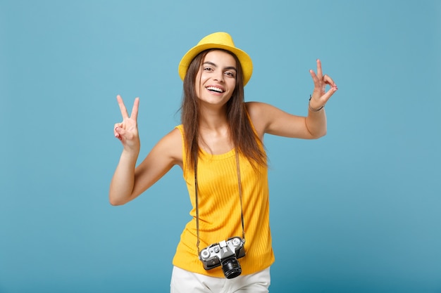 Mujer turista en ropa casual de verano amarillo y sombrero con cámara de fotos en azul