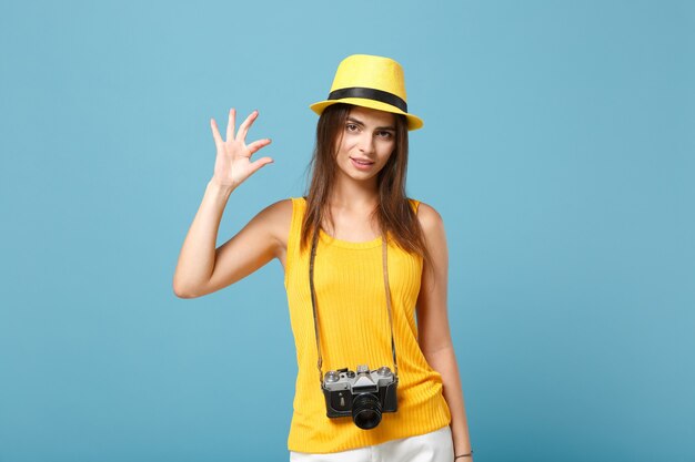 Mujer turista en ropa casual de verano amarillo y sombrero con cámara de fotos en azul