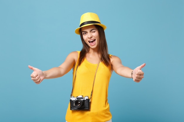 Mujer turista en ropa casual de verano amarillo y sombrero con cámara de fotos en azul