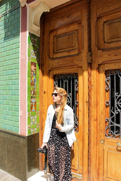 Foto mujer turista rubia con gafas de sol en la calle con una cámara