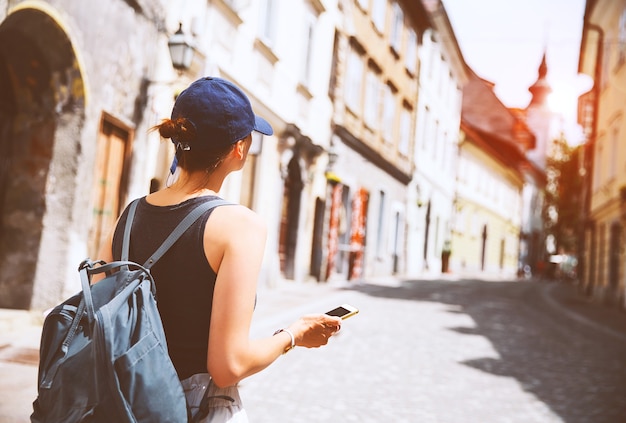 Foto mujer turista con taza de café con teléfono inteligente en la calle medieval en la ciudad vieja de ljubljana
