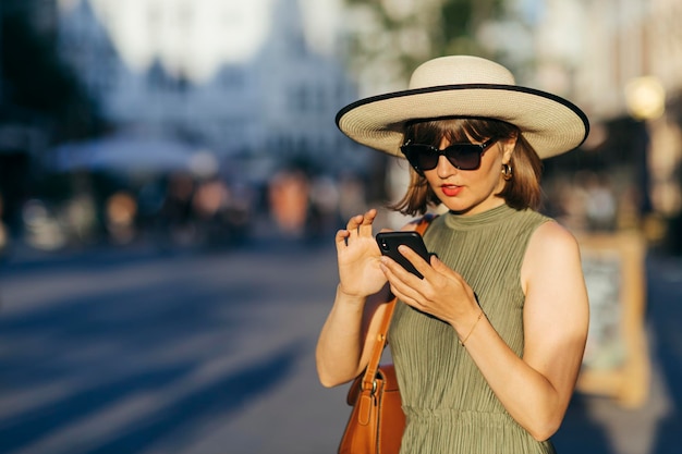 Foto mujer turista con teléfono móvil caminando por la ciudad en un día soleado