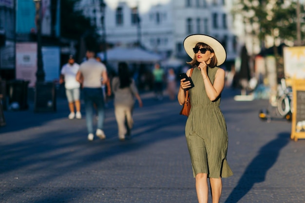 Foto mujer turista con teléfono móvil caminando por la ciudad en un día soleado