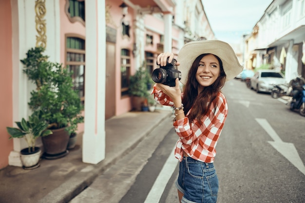 Mujer turista toma una cámara mientras camina por la ciudad