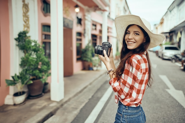 Mujer turista toma una cámara mientras camina por la ciudad