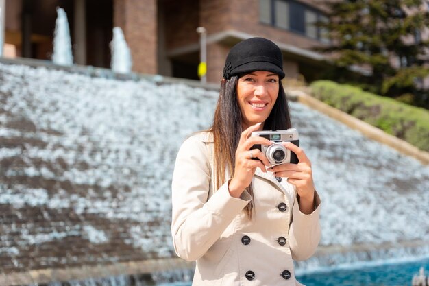 Una mujer turista tomando fotos en sus vacaciones de verano en la ciudad junto a una fuente