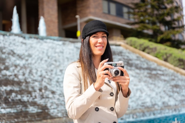 Una mujer turista tomando fotos en sus vacaciones de verano en la ciudad junto a una fuente