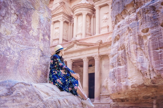 Mujer turista en vestido de color y sombrero disfrutando del Tesoro, Al Khazneh en la antigua ciudad de Petra, Jordania.