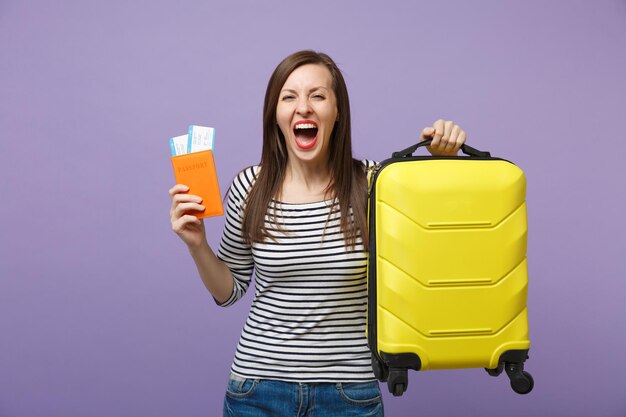Mujer turista viajera con ropa informal a rayas posando aislada en un retrato de estudio de fondo morado violeta. Pasajero que viaja al extranjero para viajar en escapada de fin de semana. Concepto de viaje de vuelo aéreo.