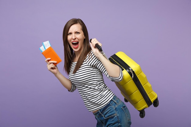 Mujer turista viajera con ropa informal a rayas posando aislada en un retrato de estudio de fondo morado violeta. Pasajero que viaja al extranjero para viajar en escapada de fin de semana. Concepto de viaje de vuelo aéreo.