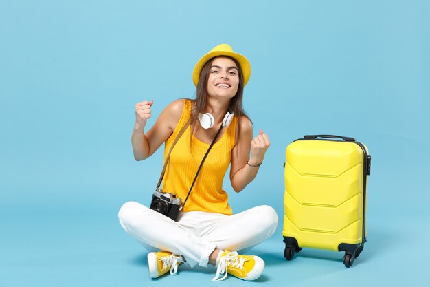 Mujer turista viajero en ropa casual amarilla, sombrero con cámara de fotos maleta en azul