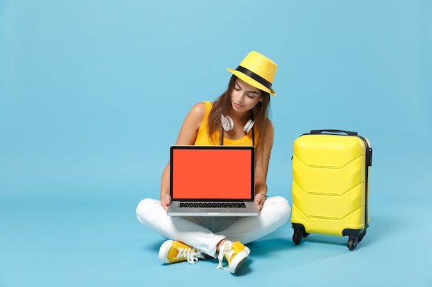 Mujer turista viajero en ropa casual amarilla, sombrero con maleta cámara de fotos de pc portátil en azul