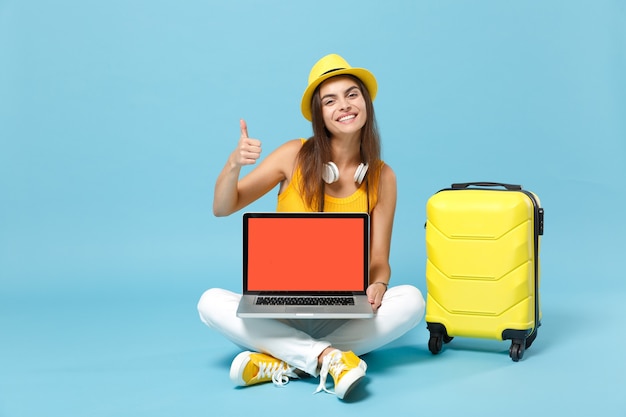 Mujer turista viajero en ropa casual amarilla, sombrero con maleta cámara de fotos de pc portátil en azul