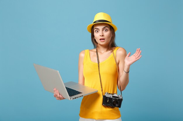 Mujer turista viajero en ropa de verano amarillo, sombrero con ordenador portátil en azul